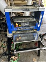 Front view of Mastercraft planer on stand, shows infeed table and accumulated sawdust