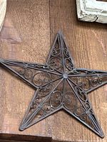 Front view of metal scrollwork wall star on wooden background