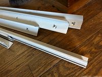 Set of white aluminum corner moldings on wooden floor