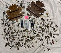 Full lot showing two maple-leaf racks, loose spoons and forks, packaged spoons