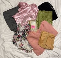 All textiles laid out, showing grey sheet, pink satin curtain, green panel, floral panel, peach fabric, mustard piece and boxed kitchen set