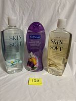 Front view of three unopened bath products: two Avon Skin So Soft bath oils and one Softsoap body wash
