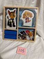 front of sealed wooden dress-up set showing two pup figures and outfit pieces
