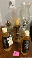 lot overview showing both oil lamps, candle holder and two bottles of lamp oil