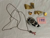 Front view of all items on white background, shows necklace, clip watch and four pins