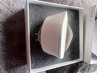 Bell Wi-Fi 6E Pod inside open box on grey felt insert, side view showing integrated prongs