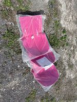 Three sealed magenta belly pan protectors laid out on ground