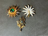 Overview of all three brooches on leather surface