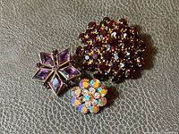 Group shot of all three brooches on leather surface