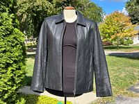 Front view of black lambskin jacket on mannequin, showing collar, zip closure, and overall condition