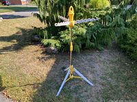 Full view of drying rack set up on lawn showing tripod base and arms extended