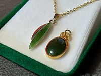 Close-up of both pendants showing jade stones and gold-tone settings