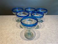 Front angled view of all six glasses highlighting blue rims and overall shape