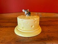 Front view of yellow cheese cloche with mouse on lid
