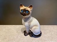 Full view of ceramic Siamese cat figurine seated on tabletop