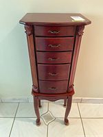Front view of five-drawer wooden jewelry armoire on legs