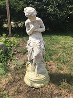 Front view of seated lady statue showing weathered surface and missing arm