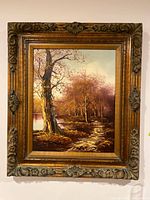 Full view of framed painting showing landscape and ornate carved wood frame