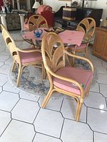 Four rattan bentwood chairs around glass table, rugs and other furniture visible