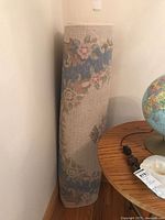 Rolled area rug showing beige backing and floral border pattern