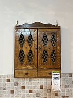 Front view of wooden spice rack showing doors, drawers, and hanging loops