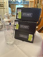 Three Stuart branded boxes and one crystal highball glass on table