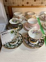 Six teacup and saucer sets arranged on countertop