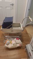 Side view of white doll buggy, chrome frame, bag of plush toys in front