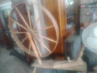 Full view of wooden spinning wheel showing drive wheel, bench and spindle assembly