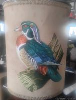 Front view of metal wastebasket showing wood duck graphic and decorative trim