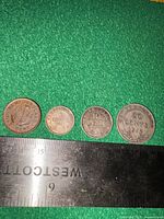 Front view of four Newfoundland coins with ruler for scale
