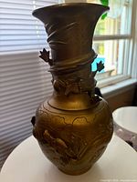 Side view of brass vase showing raised dragon motifs and overall form