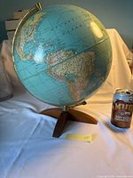 Full view of Weber Costello globe on wooden base with can for scale