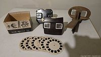 All items in lot: two View-Master viewers, wooden stereoscope, box, seven reels