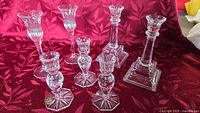 All seven Bohemia Crystal candlestick holders displayed on red cloth