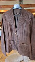 Front view of brown leather Danier jacket on hanger