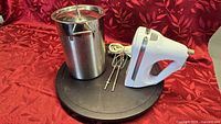 Overall lot showing stainless steel pot with lid, KitchenAid hand mixer and black lazy Susan