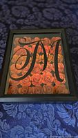 Front view of 8x10 black shadow box with orange paper roses and black monogram M
