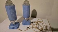 Pair of blue ceramic lamps with cords on table