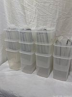 Eleven stacked clear plastic containers with lids