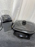 Electric skillet with lid beside popcorn maker