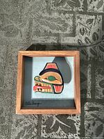 Front view of framed cedar relief showing carving, frame and artist signature