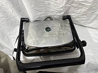 Panini press closed, top stainless lid visible