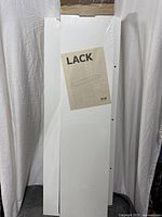 Front view of three white shelves, one in original wrap with IKEA Lack label