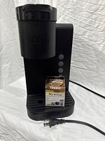 Front view of black Keurig K-Express Essentials coffee maker with My K-Cup reusable filter box and power cord