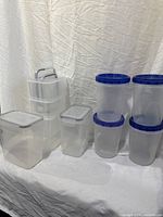 All nine containers arranged: four round with blue lids, five rectangular latch-lid units