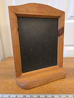 Front view of wood framed chalkboard showing floral painted details and ledge