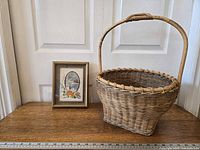 Needlepoint artwork and wicker basket side by side for scale against 36" ruler