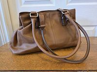 Full view of brown leather satchel showing handles and body