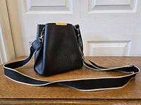 Front view of black PU leather bucket shoulder bag with strap displayed
